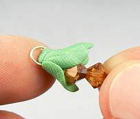 Bicone beads on a head pin with green clay wrapped around wire